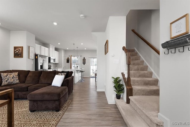 living area with stairway, recessed lighting, wood finished floors, and baseboards