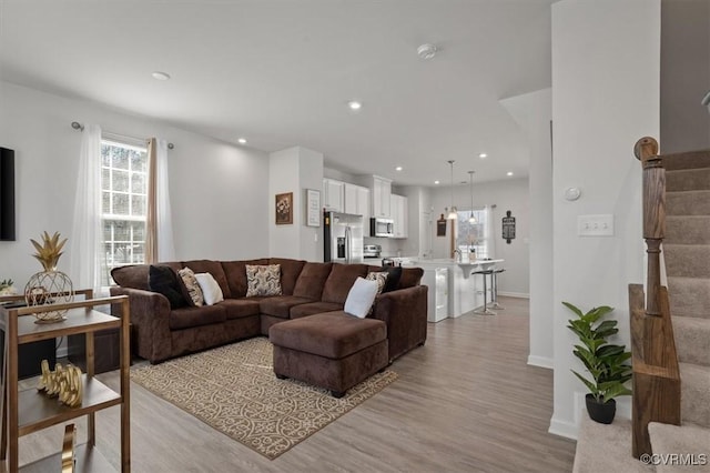 living area with stairway, recessed lighting, baseboards, and light wood-style floors