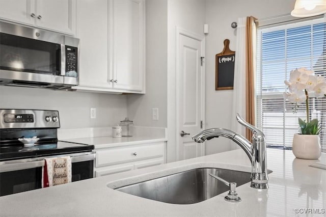 kitchen featuring a sink, appliances with stainless steel finishes, light countertops, and white cabinetry