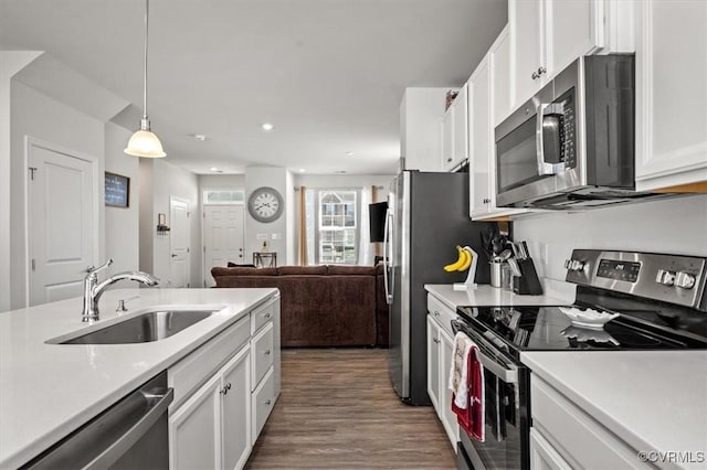 kitchen with a sink, appliances with stainless steel finishes, light countertops, and white cabinetry