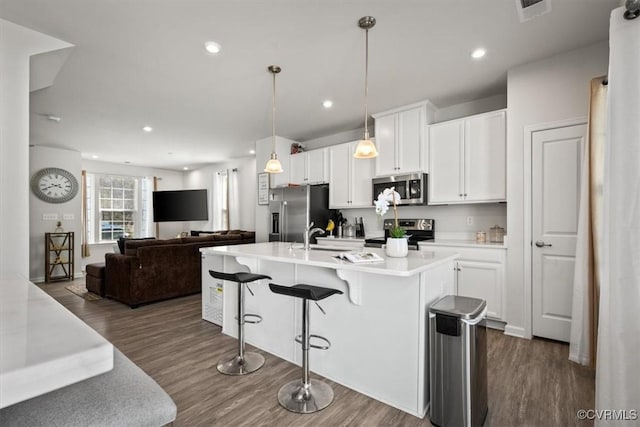 kitchen with a kitchen breakfast bar, white cabinets, dark wood-style flooring, and stainless steel appliances