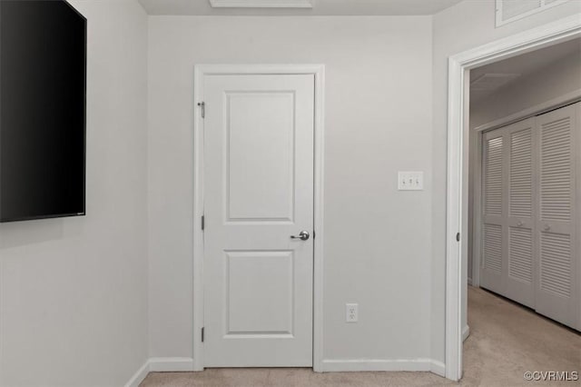 hallway with visible vents, baseboards, and light colored carpet