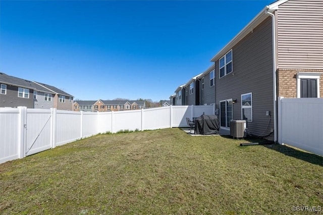 view of yard featuring a residential view, central AC, and a fenced backyard