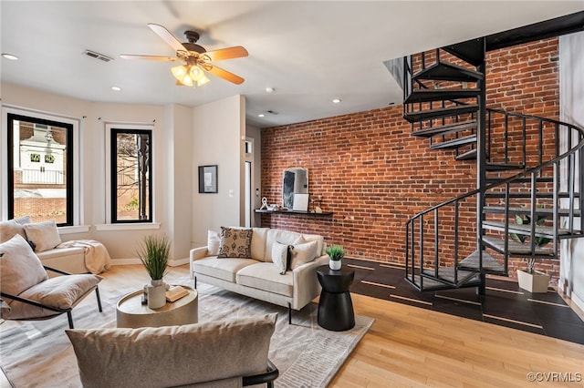 living room with visible vents, brick wall, baseboards, stairs, and wood finished floors