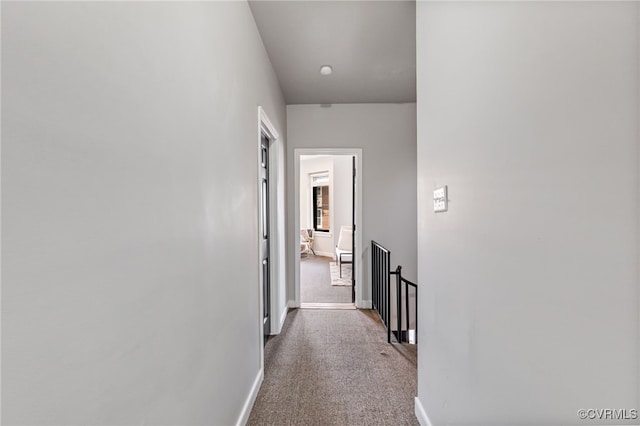 hallway featuring carpet flooring, an upstairs landing, and baseboards