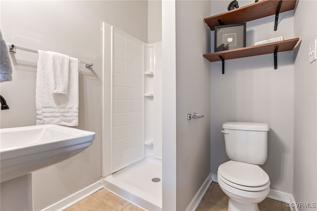 bathroom featuring tile patterned floors, tiled shower, toilet, and baseboards