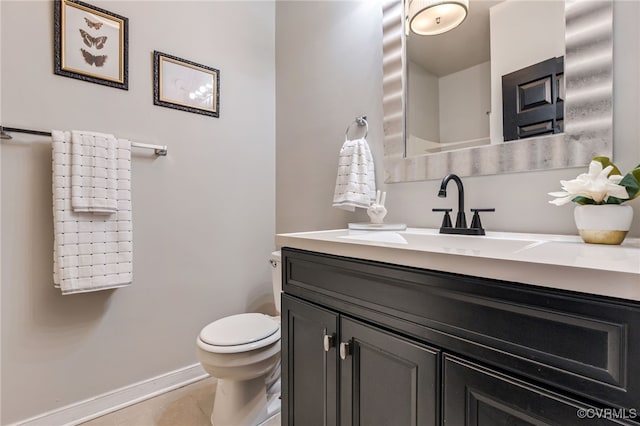 half bathroom featuring tile patterned flooring, toilet, vanity, and baseboards