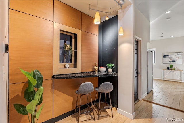 bar with decorative light fixtures, baseboards, wood finished floors, and recessed lighting