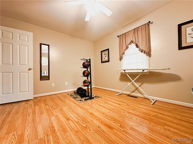 exercise room featuring baseboards, a ceiling fan, and light wood finished floors