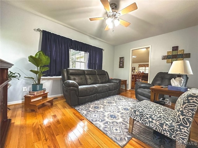 living area with baseboards, ceiling fan, and wood-type flooring