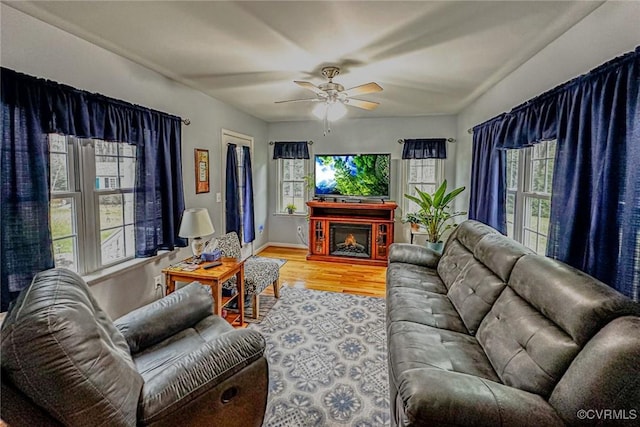 living room with baseboards, a fireplace, wood finished floors, and a ceiling fan