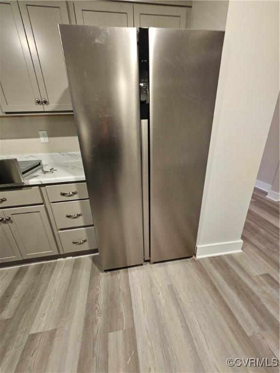 kitchen featuring light wood-type flooring, light countertops, gray cabinets, and freestanding refrigerator