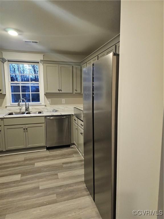 kitchen featuring visible vents, gray cabinetry, a sink, light countertops, and appliances with stainless steel finishes