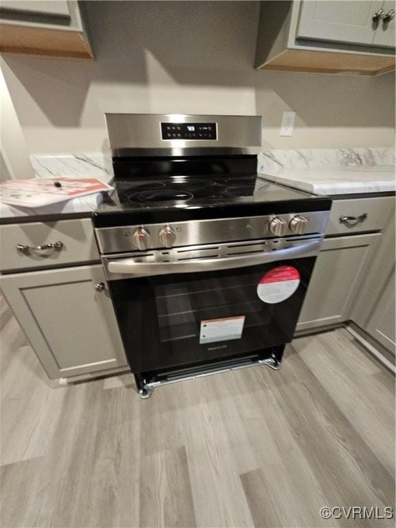 interior details featuring stainless steel electric stove, light wood-style flooring, and light countertops