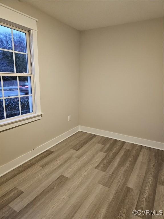 spare room featuring baseboards and dark wood-style flooring