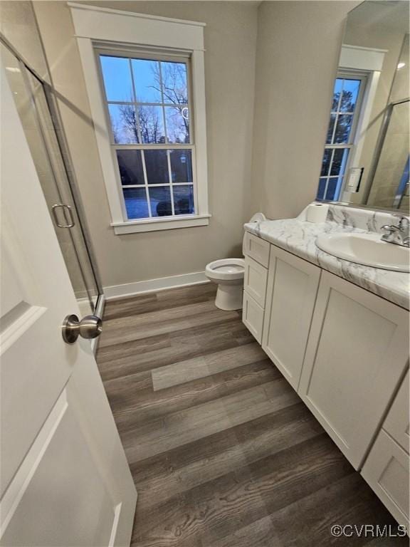 full bathroom featuring toilet, wood finished floors, a shower stall, baseboards, and vanity