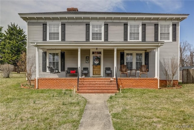 italianate-style house featuring a porch, a chimney, and a front yard