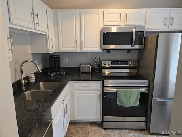 kitchen with a sink, dark stone countertops, white cabinetry, and stainless steel appliances