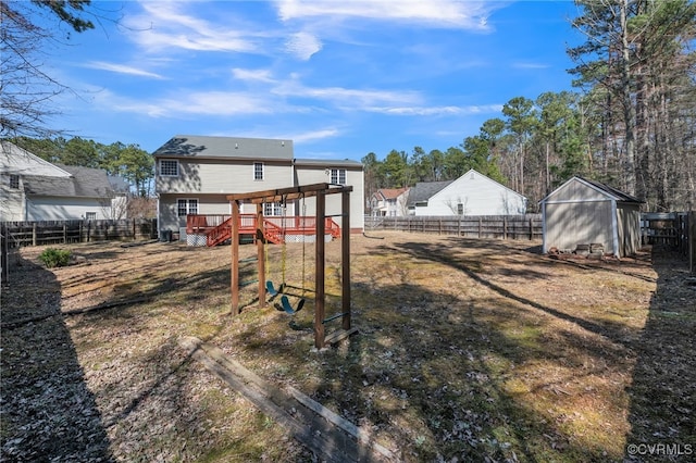 view of yard with an outbuilding, a shed, a wooden deck, and a fenced backyard