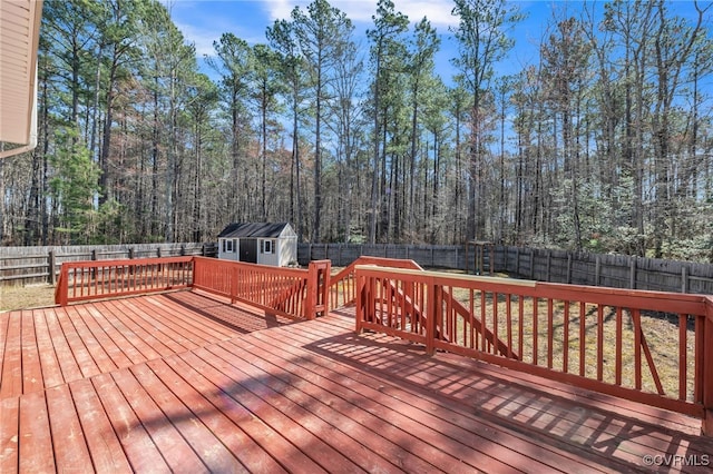 wooden terrace featuring an outbuilding, a fenced backyard, a shed, and a view of trees