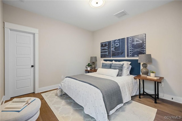 bedroom featuring visible vents, baseboards, and wood finished floors