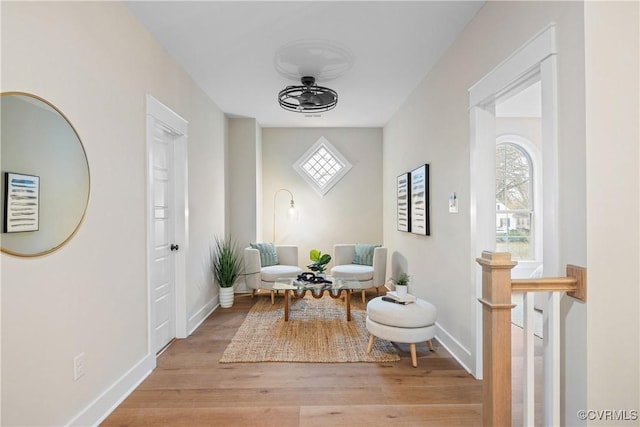 living area featuring baseboards, light wood-style flooring, and a ceiling fan