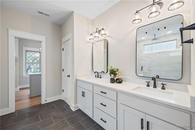 full bathroom featuring double vanity, visible vents, a marble finish shower, and a sink