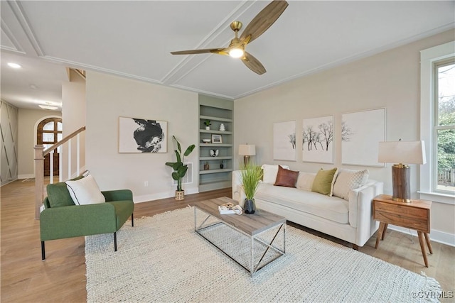 living area featuring built in shelves, baseboards, and wood finished floors