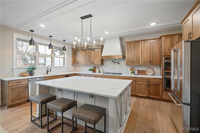 kitchen featuring custom exhaust hood, light wood-style flooring, appliances with stainless steel finishes, and brown cabinetry