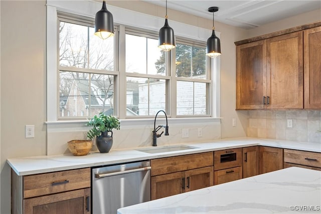 kitchen featuring decorative light fixtures, dishwasher, decorative backsplash, brown cabinetry, and a sink