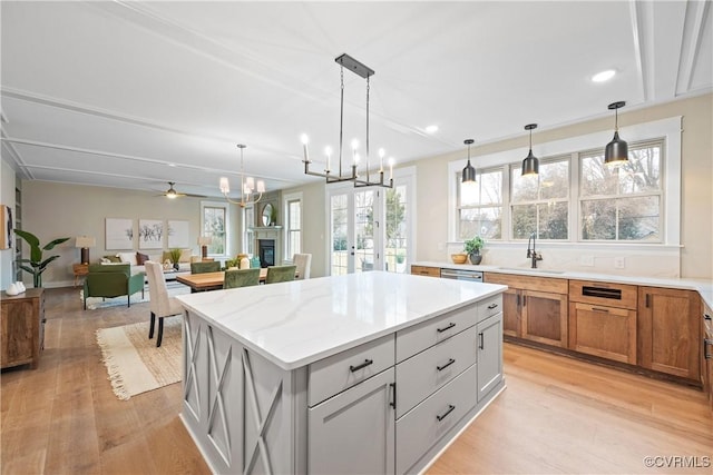 kitchen featuring brown cabinetry, light wood-style flooring, a kitchen island, and a sink