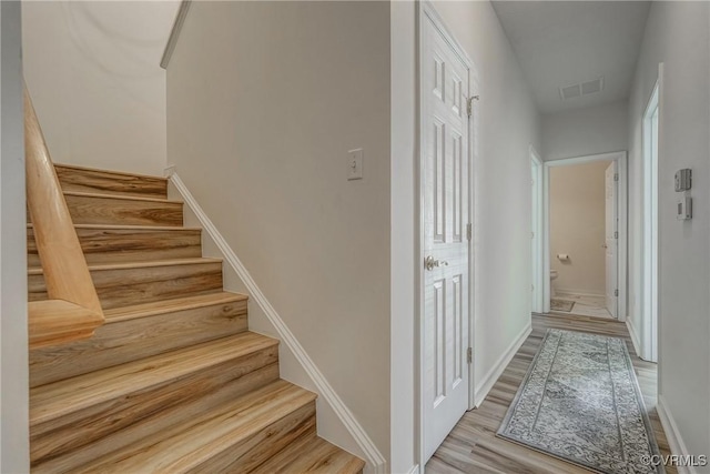 staircase featuring visible vents, baseboards, and wood finished floors