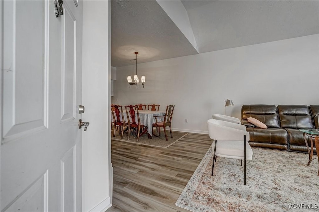 living room with a chandelier, baseboards, and wood finished floors