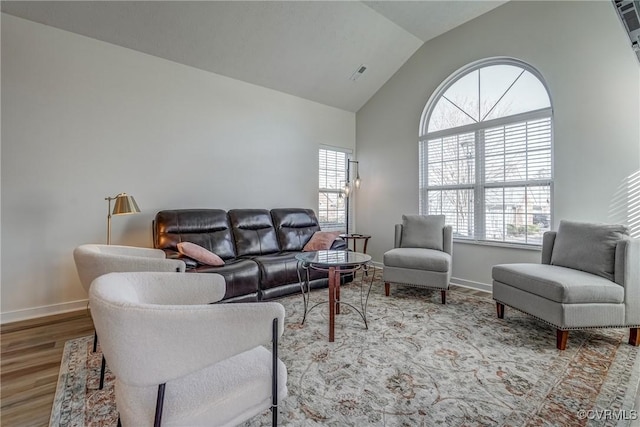 living area with visible vents, high vaulted ceiling, baseboards, and wood finished floors