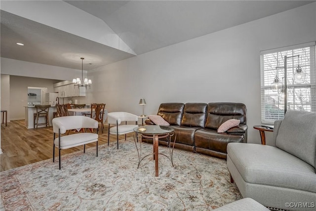 living room featuring an inviting chandelier, light wood finished floors, and vaulted ceiling