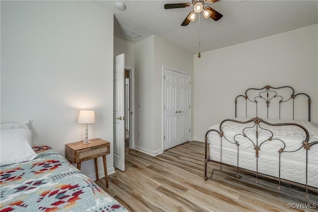 bedroom with visible vents, a ceiling fan, wood finished floors, a closet, and baseboards