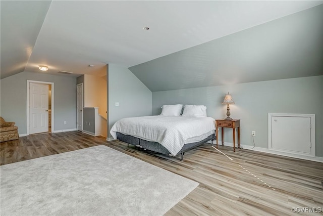 bedroom with baseboards, lofted ceiling, visible vents, and wood finished floors