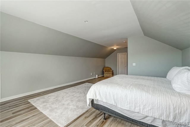 bedroom featuring baseboards, lofted ceiling, and wood finished floors