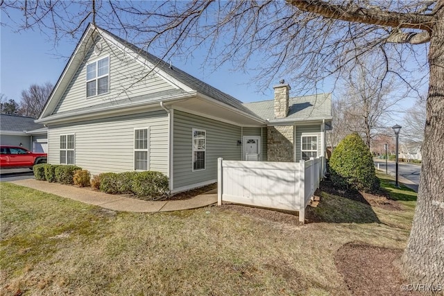 view of home's exterior featuring a chimney and a yard