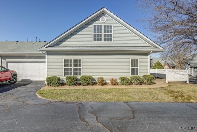 view of side of property with a garage, driveway, and fence