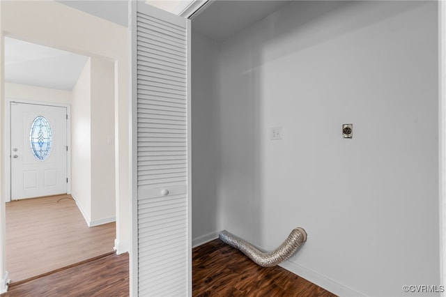 washroom featuring laundry area, electric dryer hookup, dark wood-type flooring, and baseboards