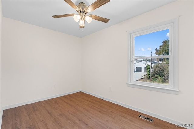 empty room with wood finished floors, baseboards, and visible vents