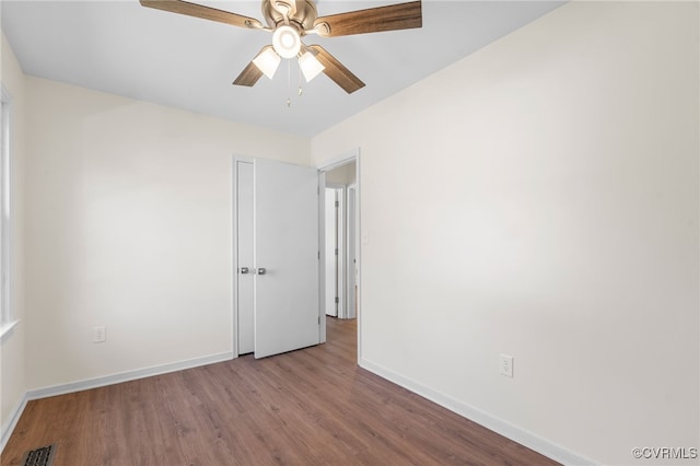 empty room with visible vents, wood finished floors, baseboards, and ceiling fan