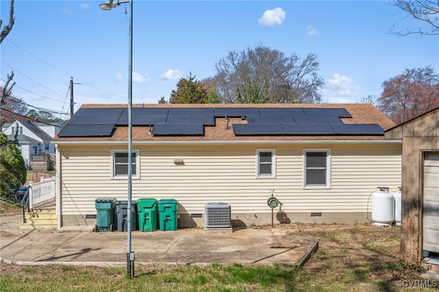 back of house featuring crawl space, roof mounted solar panels, central AC, and a shingled roof