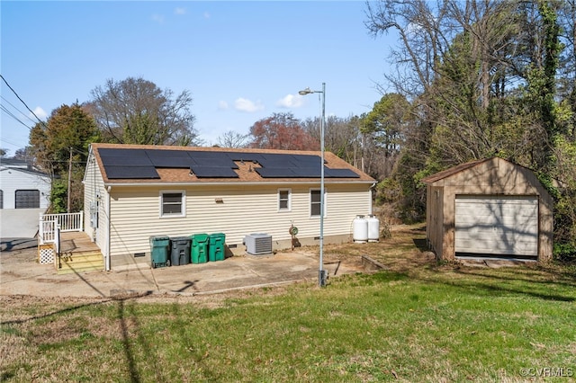 back of property with crawl space, roof mounted solar panels, a yard, and an outdoor structure