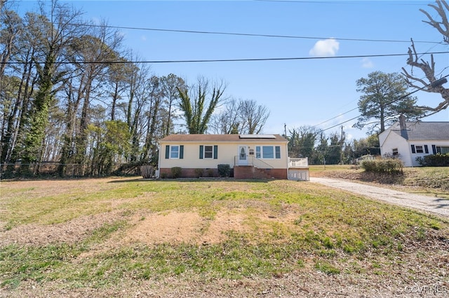 ranch-style home with a front lawn, solar panels, and driveway