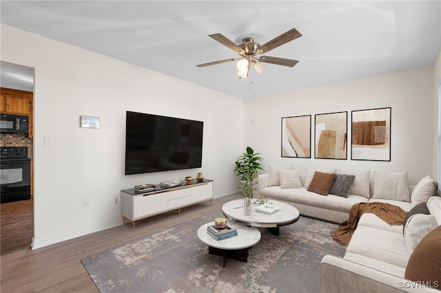 living area with baseboards, wood finished floors, and a ceiling fan