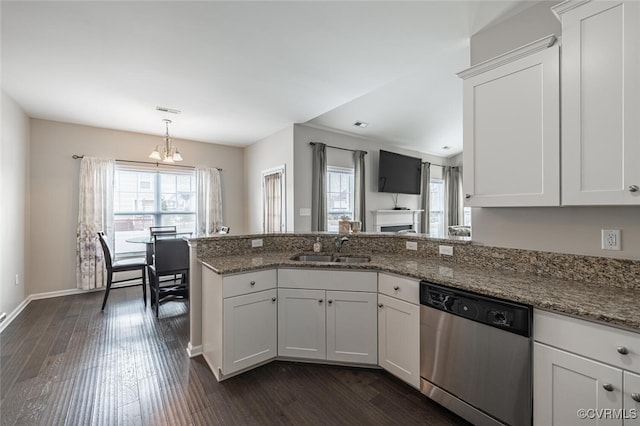 kitchen with a sink, stainless steel dishwasher, dark wood-style floors, a peninsula, and white cabinets