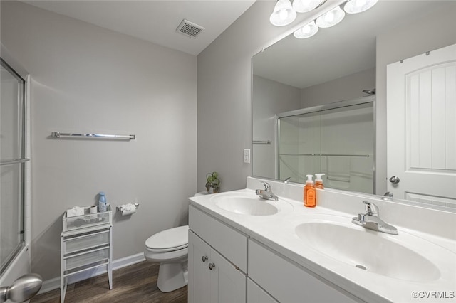 bathroom with toilet, an enclosed shower, visible vents, and a sink