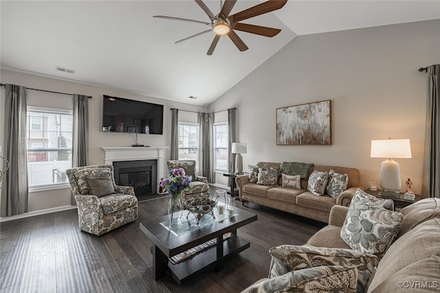 living area featuring a glass covered fireplace, plenty of natural light, a ceiling fan, and wood finished floors